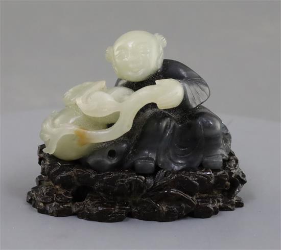 A Chinese pale celadon and grey jade figure of a seated boy, 5.7cm excluding carved wood stand